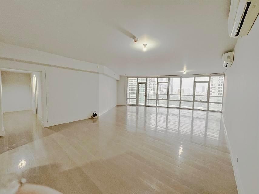 Spacious empty living room with large windows and wooden floors in a modern apartment.